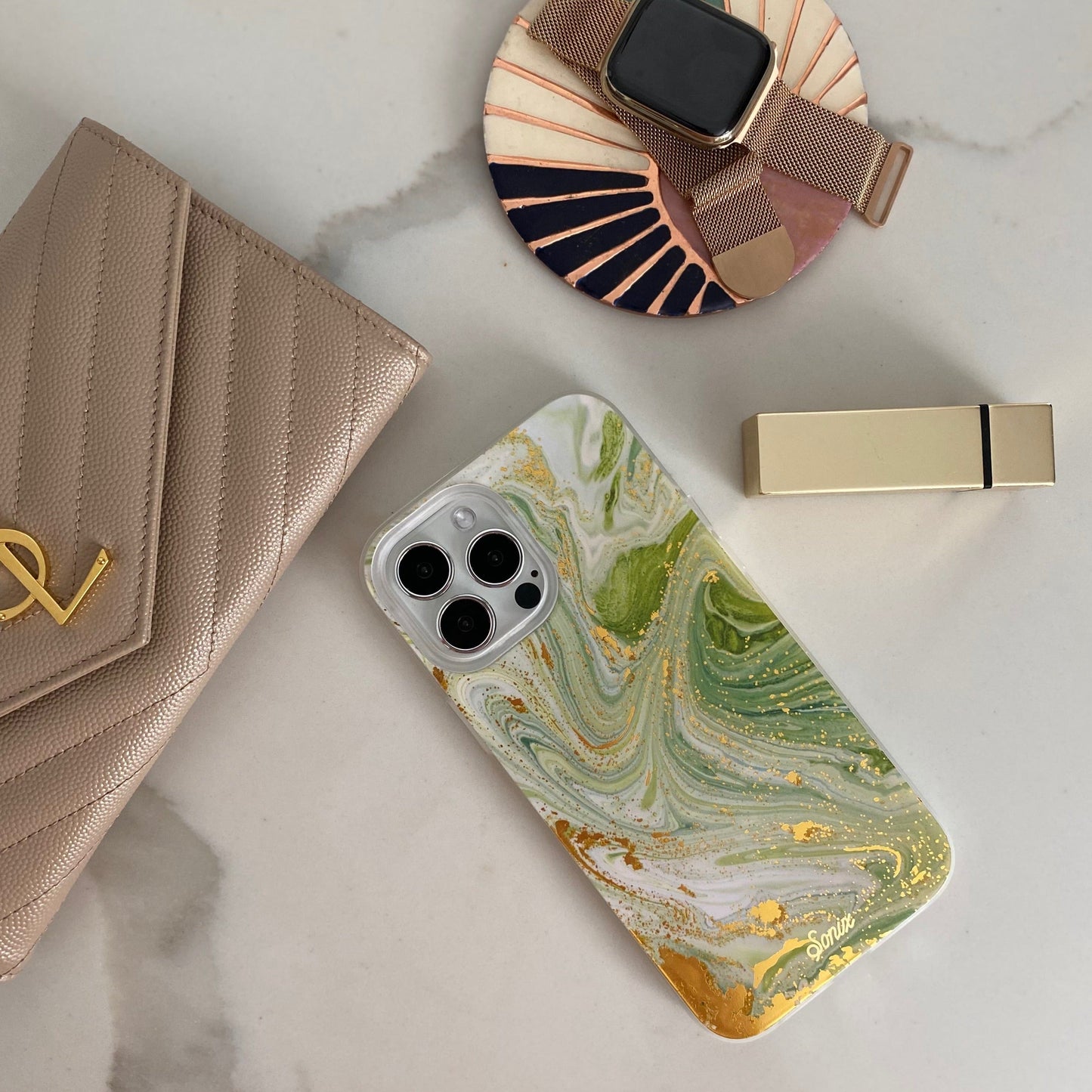 jade green marbled design with gold shimmer detailing shown on an iphone on a marble counter top