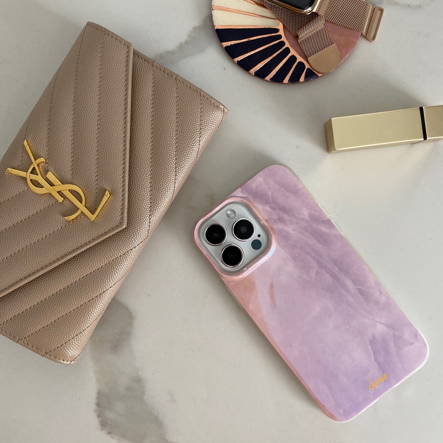 a gleaming pearl design with a pink finish shown on an iphone laying on a marble table