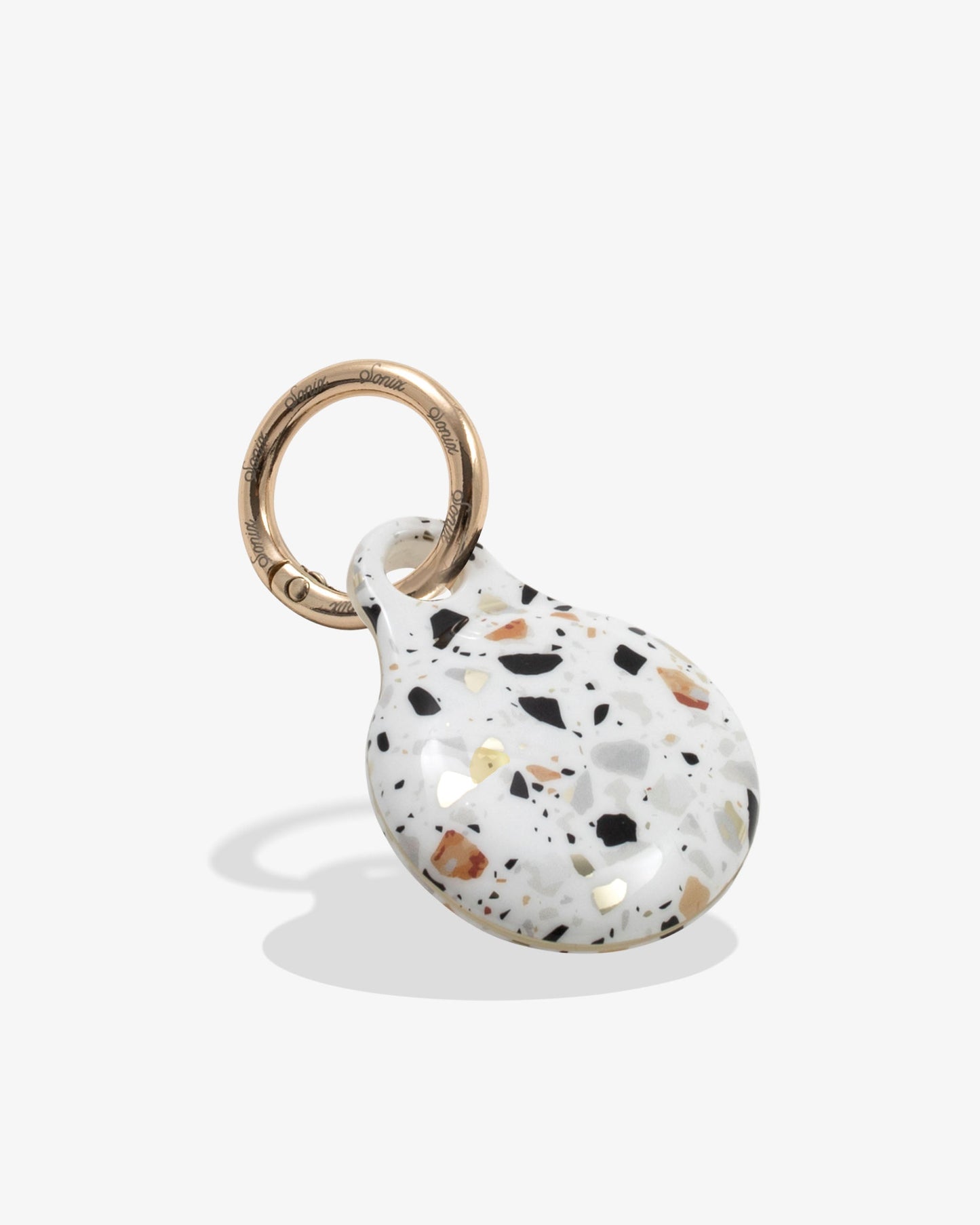 confetti air tag with gold ring with whites, blues, oranges, and black