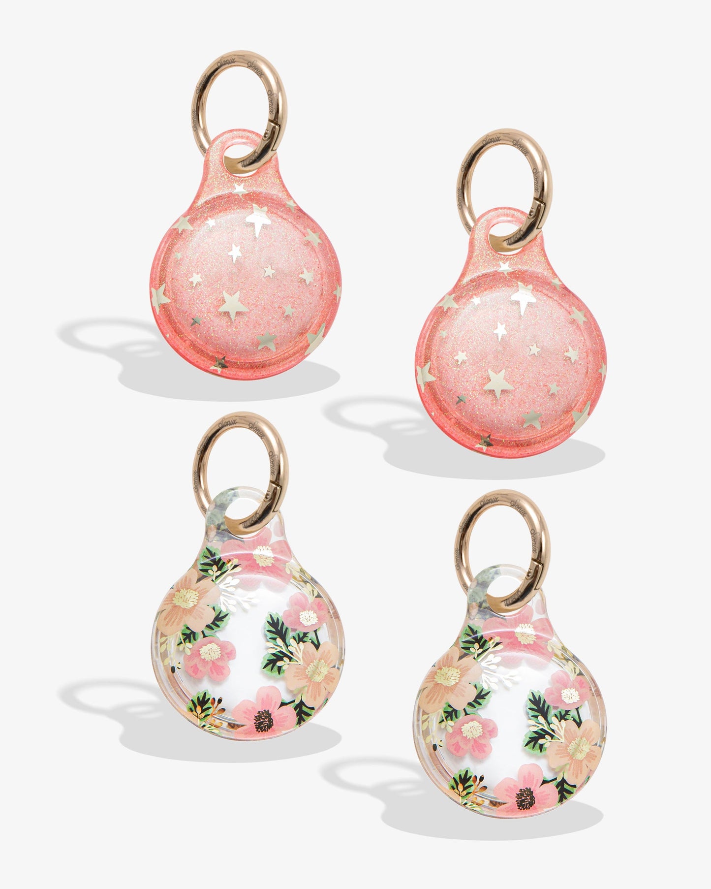 pink glitter airtag cover with metallic gold foil stars and gold ring, clear airtag cover with pink and orange flowers, green leaves and gold foil details with gold ring
