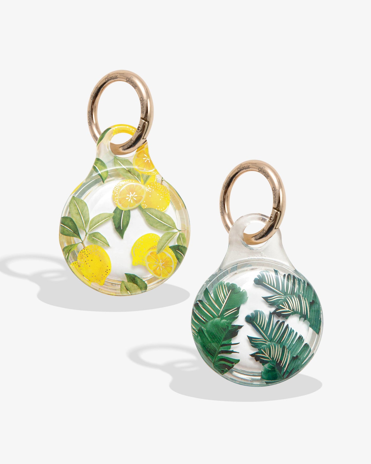 clear airtag cover with yellow lemons and green leaves with gold ring; clear airtag case with green palm leaves with gold foil detail