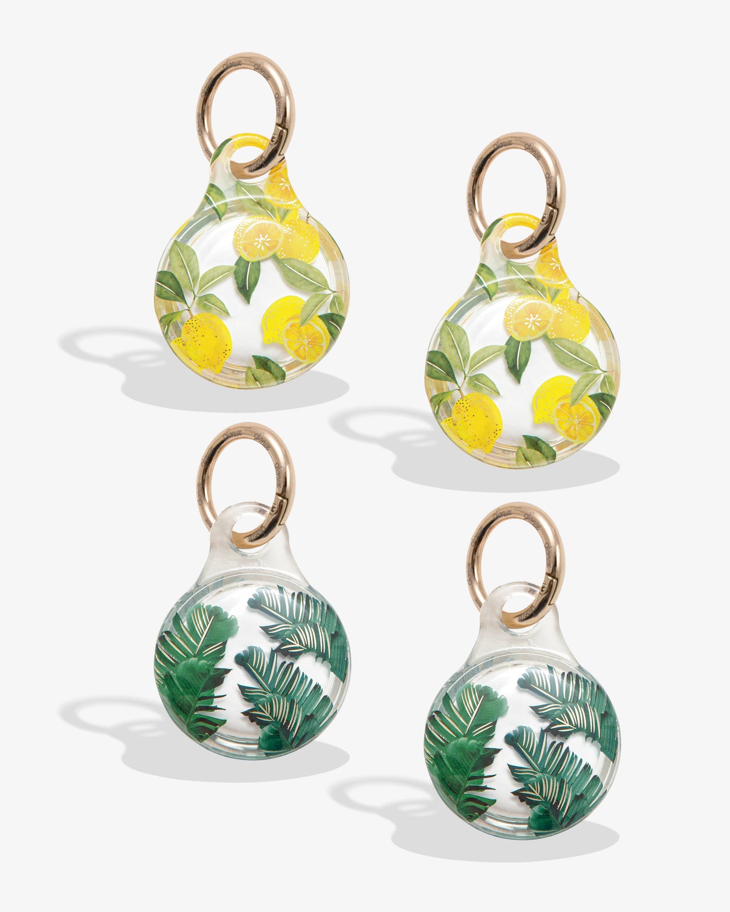 clear airtag cover with yellow lemons and green leaves with gold ring; clear airtag case with green palm leaves with gold foil detail