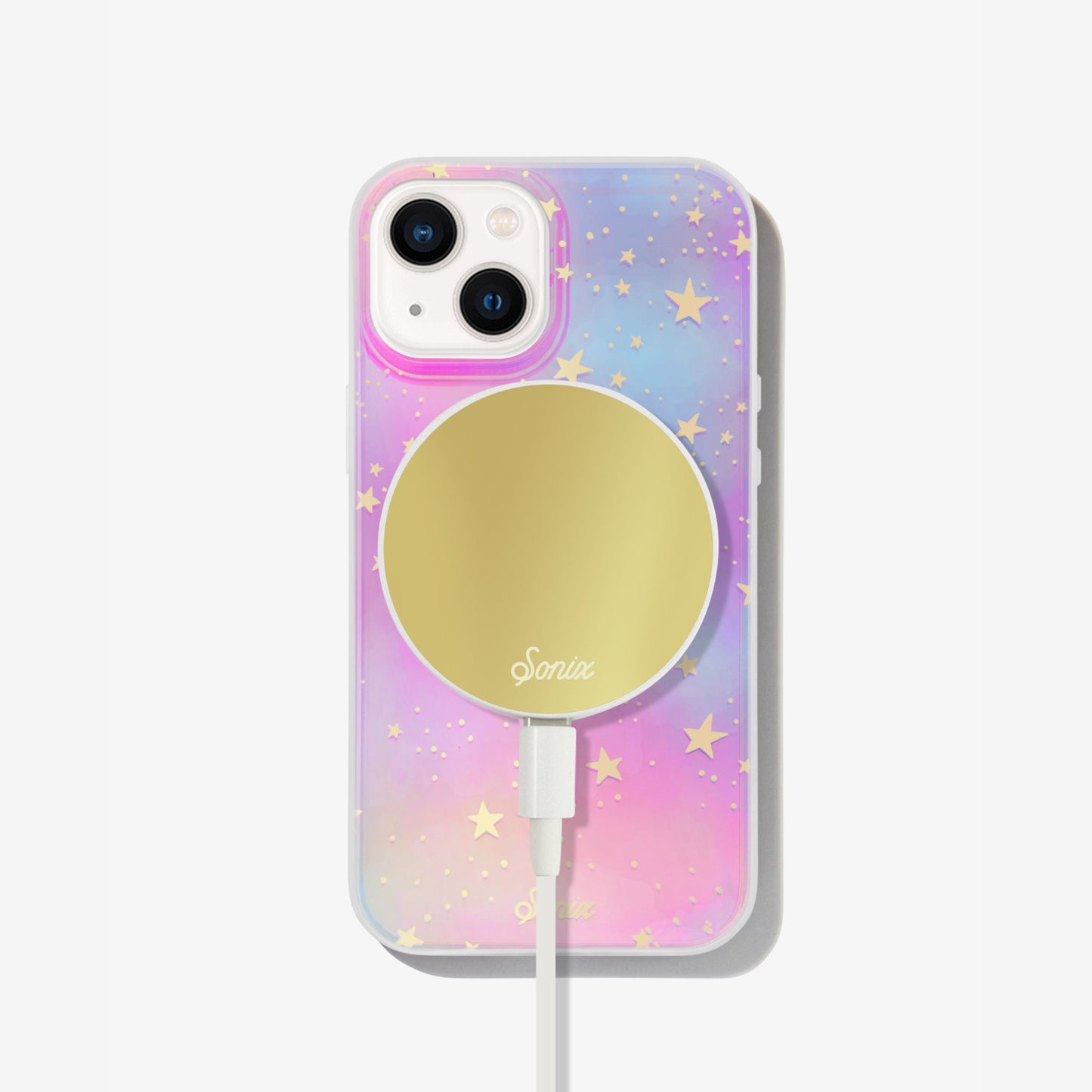 Our clear case with signature iridescent finish featuring gold foil stars shown on an iphone with a gold maglink charger on the back