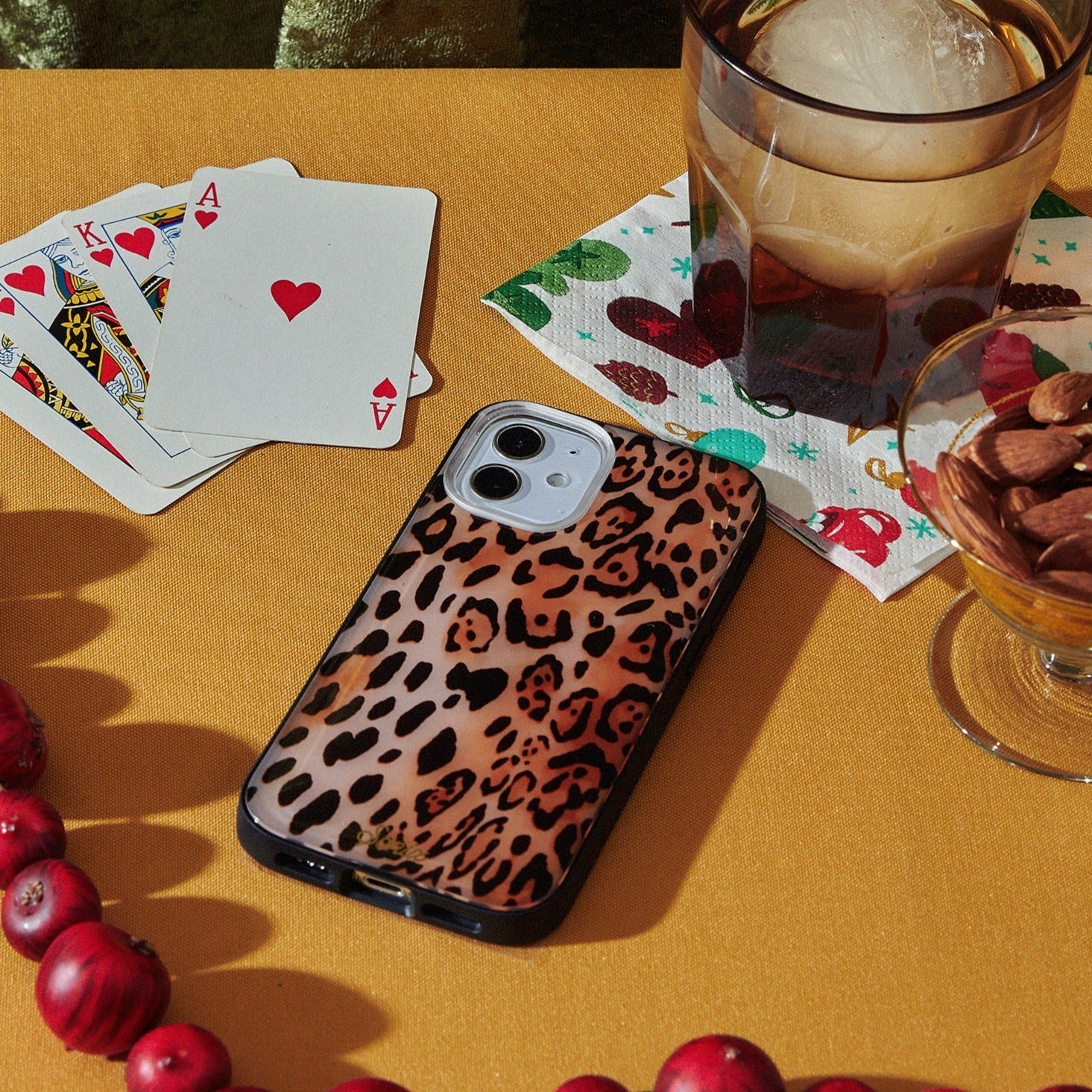 Watercolor Leopard iPhone Case modeled on table with playing cards, nuts and drink.