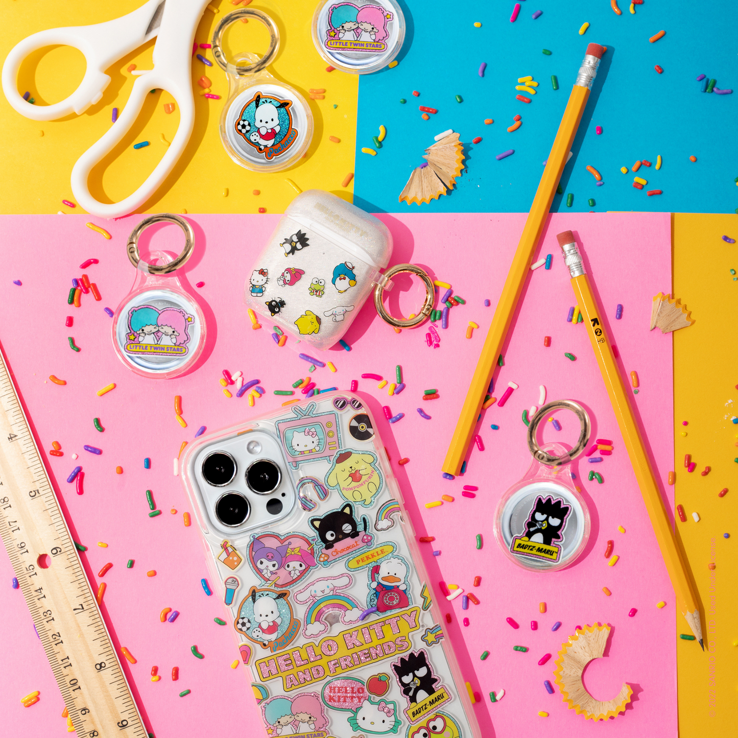  clear case with many beloved hello kitty characters featuring multi-color glitter and classic gold foiling shown on an iphone 12, airpod case, and airtag cases