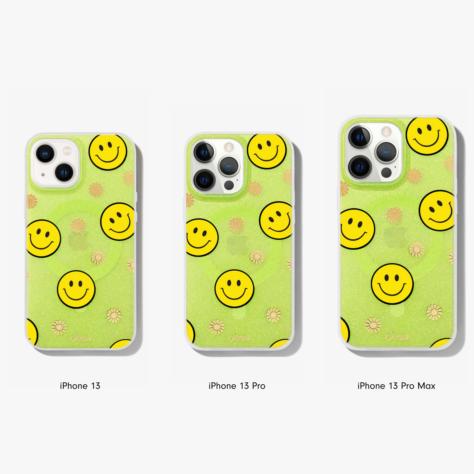 The clear yellow case infused with iridescent glitter features happy faces and signature gold foil flowers shown on an iphone 13, iphone 13 pro, and iphone 13 pro max