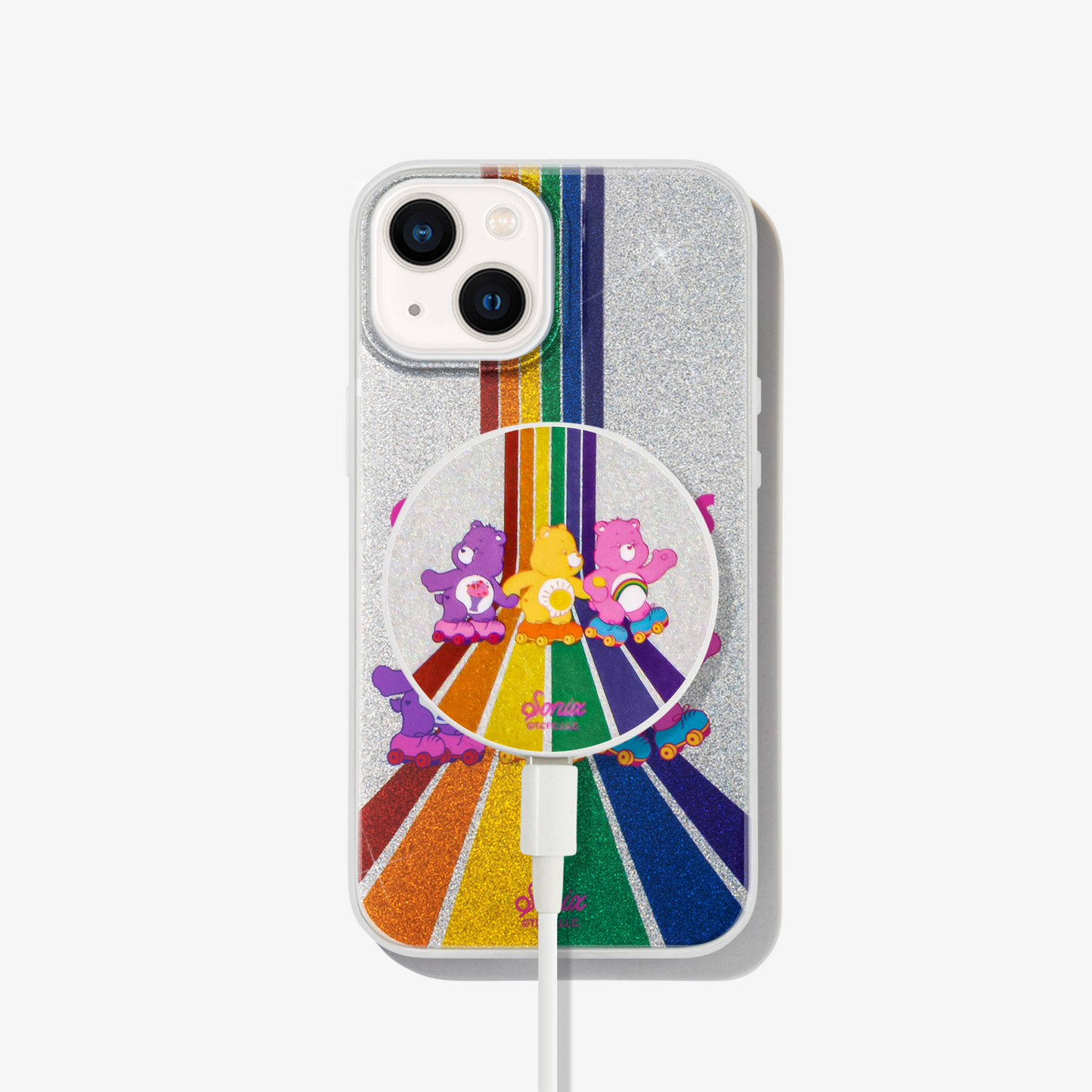 Care Bears: Share Bear, Funshine Bear, and Cheer Bear - skating down a rainbow road of glitter shown on an iphone 13 with a good vibes magsafe charger on the back