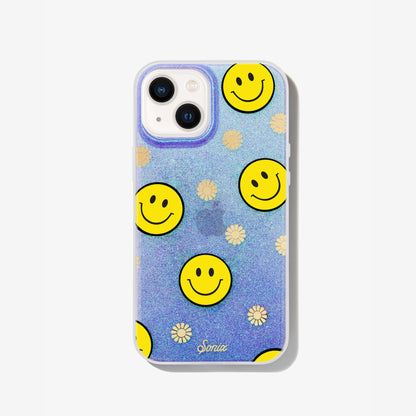 The clear purple case infused with iridescent glitter features happy faces and signature gold foil flowers shown on an iphone 13