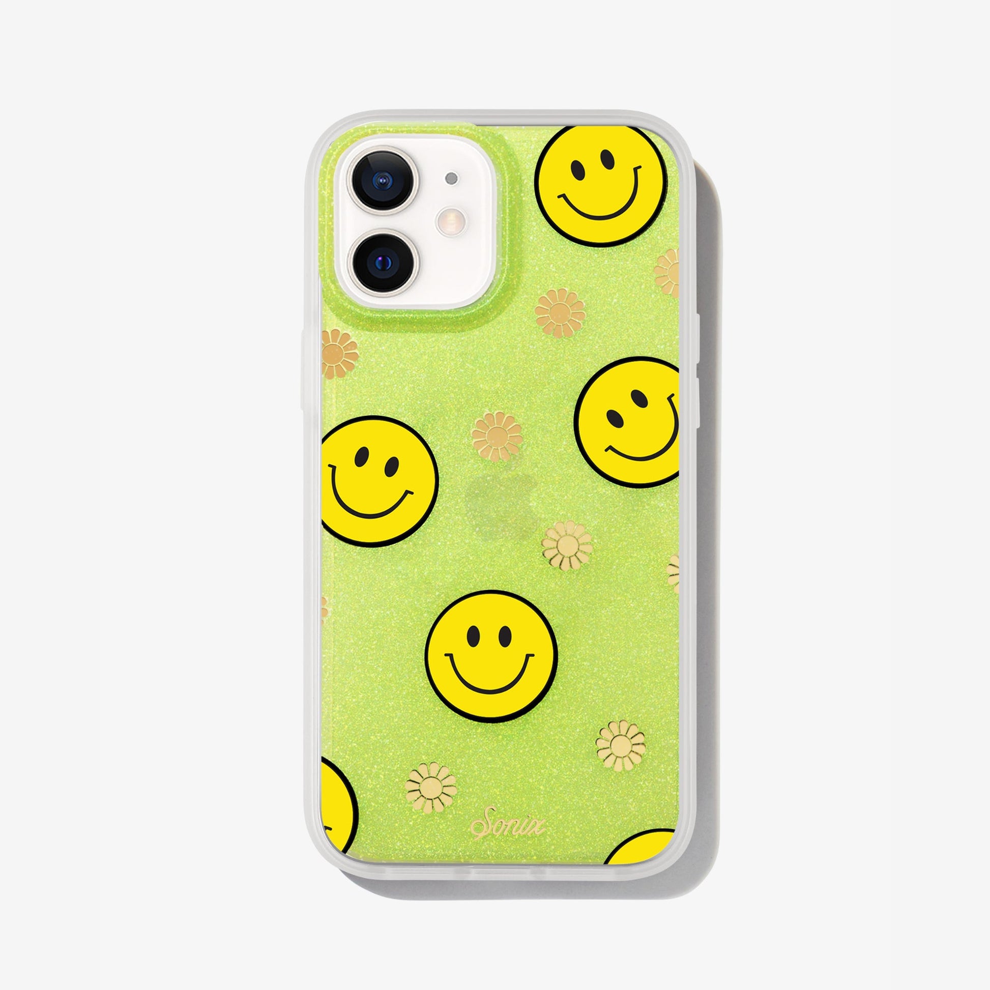 The clear yellow case infused with iridescent glitter features happy faces and signature gold foil flowers shown on an iphone 12