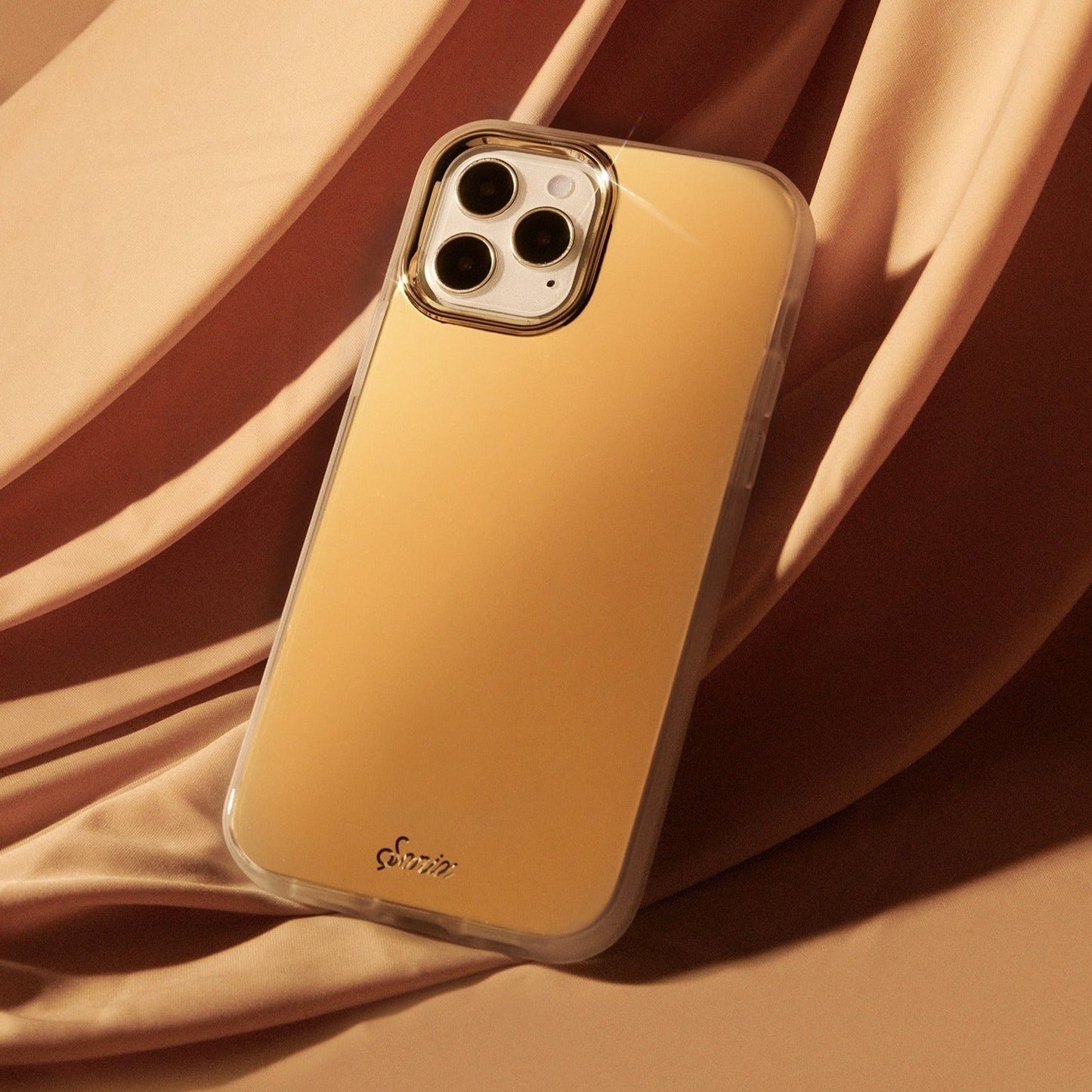 a metallic gold design shown on an iphone 12 mini with a gold satin background